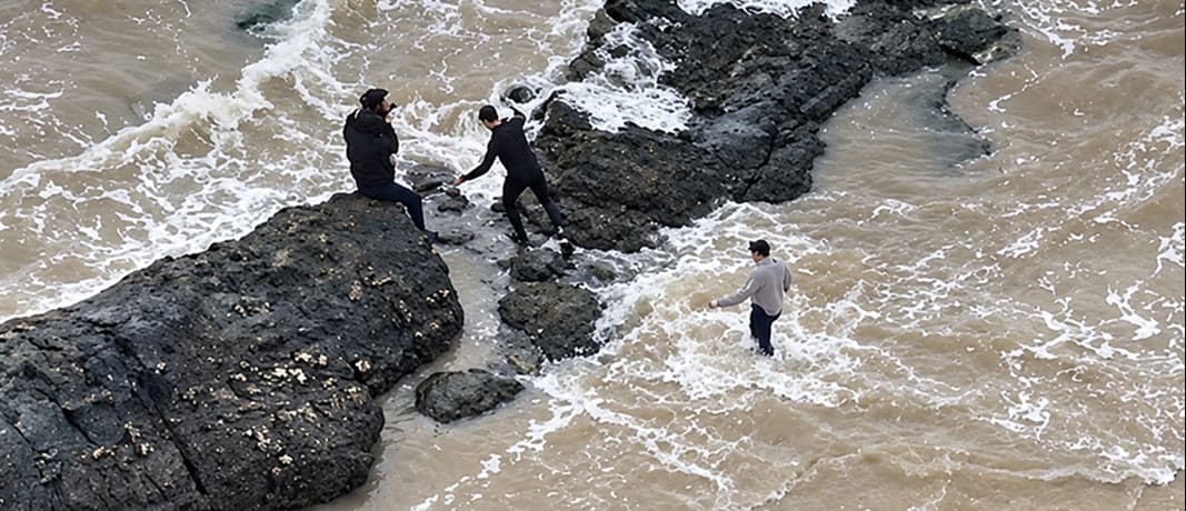 Drone view of people on the rocks and in the water of the Río de la Plata, Montevideo
